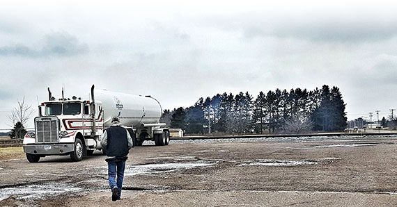 Truck Owner / Operator walking across the parking lot to his rig hauling a commercial propane tanker