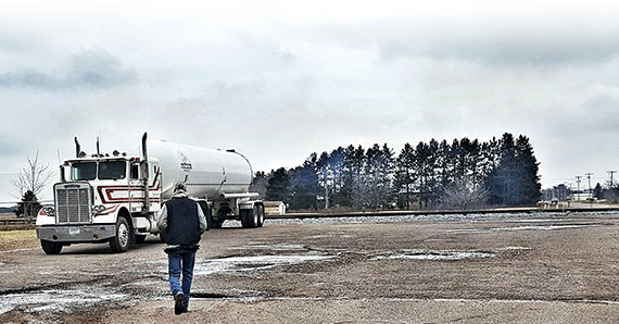 Truck Owner / Operator walking across the parking lot to his rig hauling a commercial propane tanker